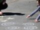 a young girl is drawing on the ground with chalk