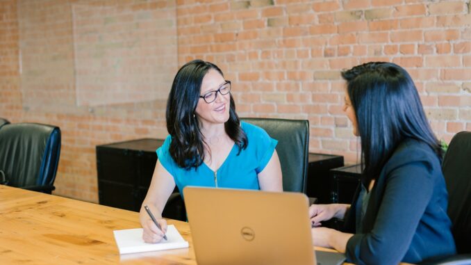 Photo by Amy Hirschi woman in teal t-shirt sitting beside woman in suit jacket