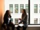 two woman sitting by the window laughing