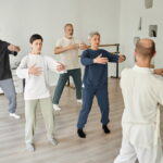 Un groupe de seniors suit attentivement un professeur pour une session de danse adulte axée sur la fluidité et l'équilibre