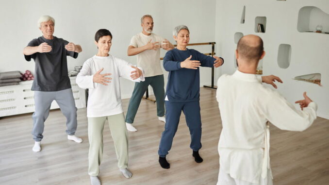 Un groupe de seniors suit attentivement un professeur pour une session de danse adulte axée sur la fluidité et l'équilibre