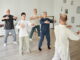 Un groupe de seniors suit attentivement un professeur pour une session de danse adulte axée sur la fluidité et l'équilibre
