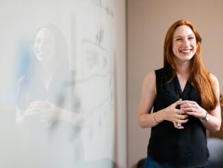 smiling woman presenting at whiteboard
