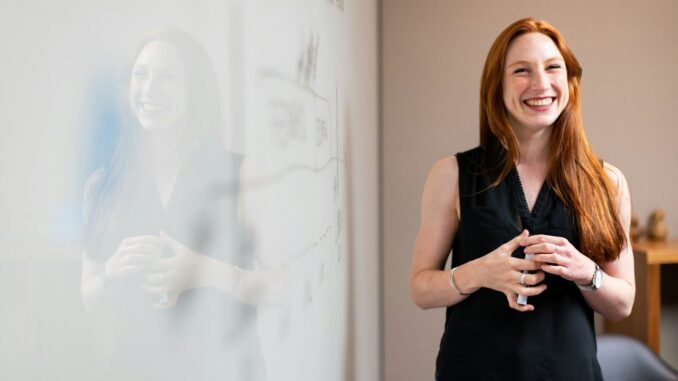 smiling woman presenting at whiteboard