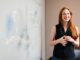 smiling woman presenting at whiteboard