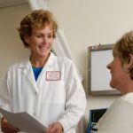 A smiling doctor in a white coat talking to a patient in a clinic