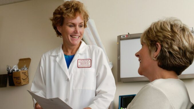 A smiling doctor in a white coat talking to a patient in a clinic