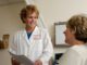 A smiling doctor in a white coat talking to a patient in a clinic