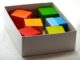 Des cubes de couleur dans une boîte blanche sur un fond clair