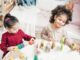 Enfants manipulant des blocs en bois sur une table dans une pièce