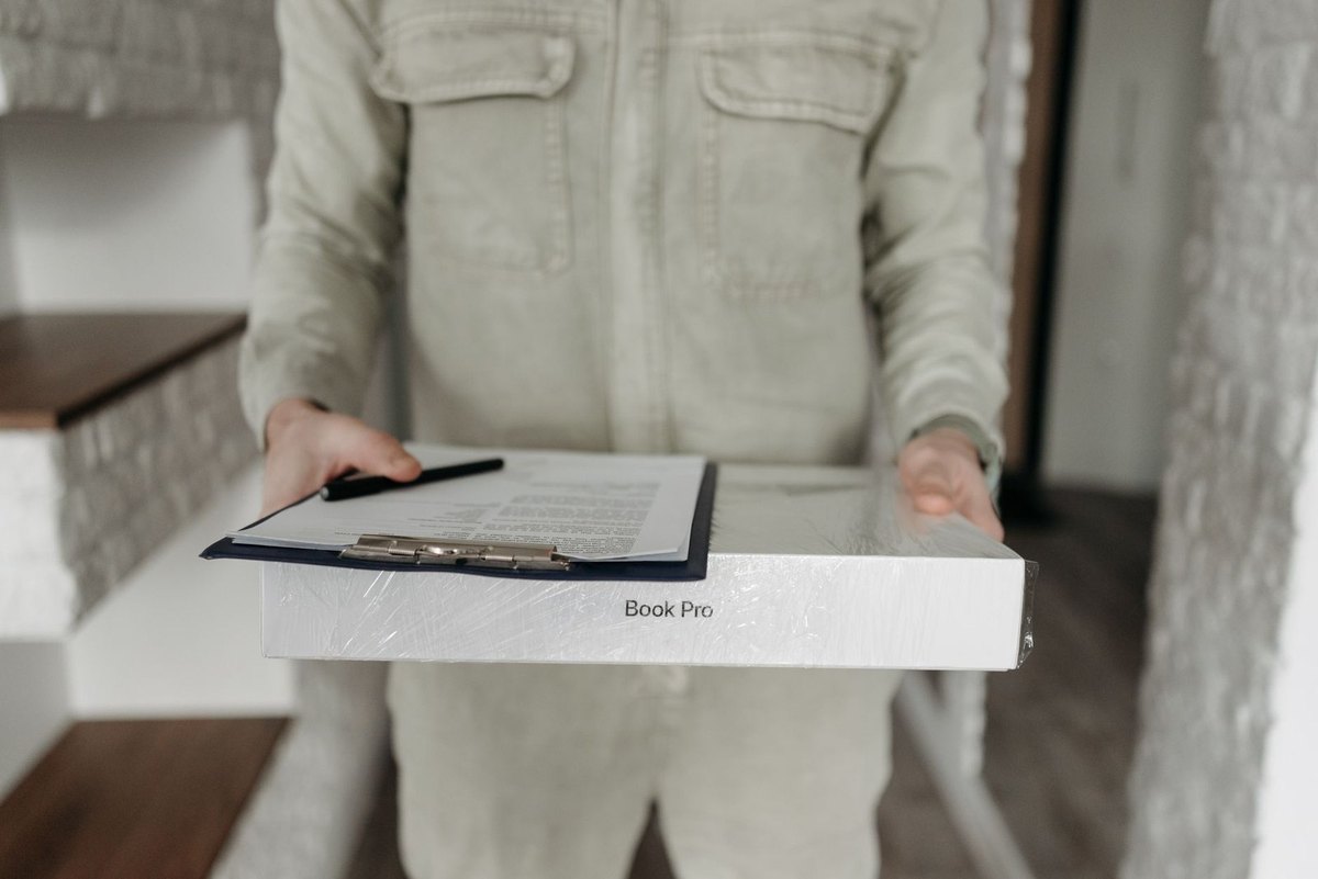 Personne en blouse blanche portant un classeur avec carnet et stylo à l'intérieur d'un bâtiment
