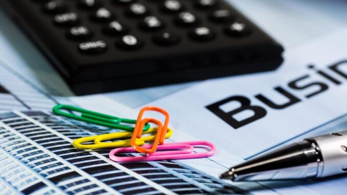 Calculatrice, papier, stylo et trombones colorés sur document d'entreprise